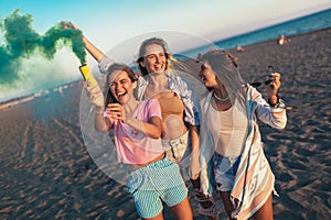 Happy friend walking on beautiful beach in summer sunset in their hands is smoke fontain