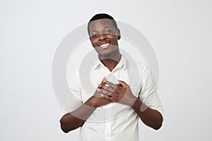 Happy friendly african man being content to hear compliment, expresses his gratitude and thanks