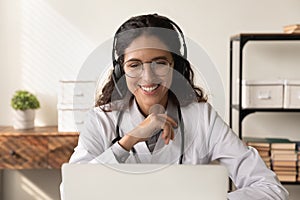 Happy friendly female physician in headphones chatting to patient