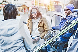 Happy friends arrived at winter vacation village with skies and snowboards - Young skiers having fun unloading the car - Extreme