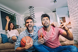 Happy friends or basketball fans watching basketball game on tv