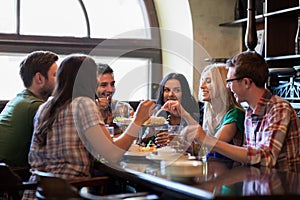 Happy friends with beer eating at bar or pub