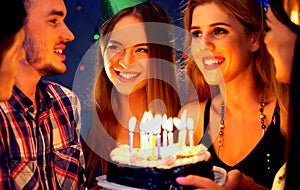 Happy friends birthday party with candle celebration cakes in club.