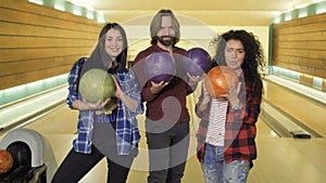 Happy friends with bowling balls in bowling club