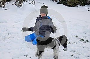 Happy friends, boy and dog ,playing in the in snow