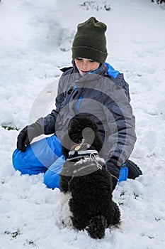 Happy friends, boy and dog ,playing in the in snow