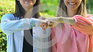 Happy friends bumping fists and smiling on camera, strong friendship gesture