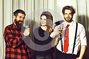 Happy friends celebrating at karaoke party. Hipster with beard in red plaid shirt singing