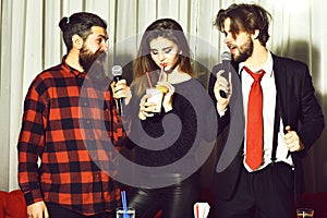 Happy friends celebrating at karaoke party in red plaid shirt and business suit singing