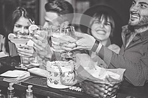 Happy friends cheering with cocktail in a vintage bar - Young people having fun toasting glasses of cocktails in a pub club