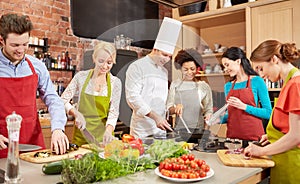 Happy friends and chef cook cooking in kitchen