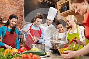 Happy friends and chef cook cooking in kitchen