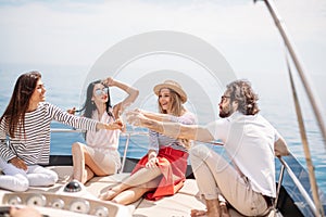 Happy friends clinking glasses of champagne and sailing on yacht