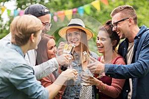 Happy friends clinking glasses at summer garden