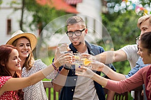 Happy friends clinking glasses at summer garden