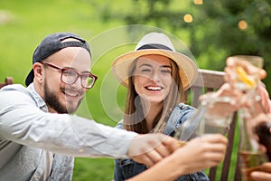 Happy friends clinking glasses at summer garden