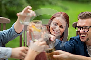 Happy friends clinking glasses at summer garden