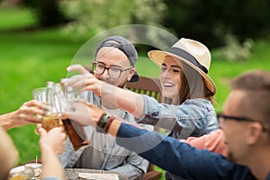 Happy friends clinking glasses at summer garden