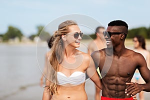 Happy friends or couples hugging on summer beach