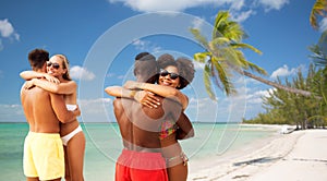 Happy friends or couples hugging on summer beach