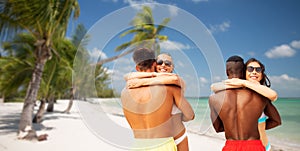 Happy friends or couples hugging on summer beach