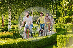 Happy friends cycling in city park.