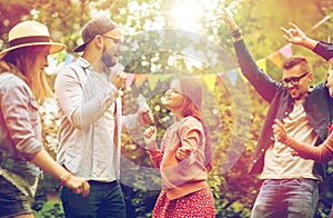 Happy friends dancing at summer party in garden