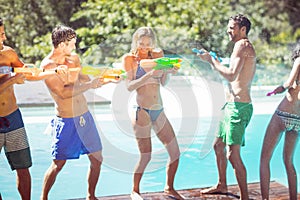 Happy friends doing water gun battle