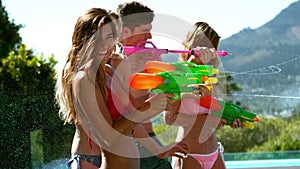 Happy friends doing water gun battle