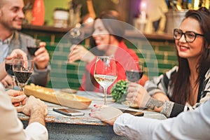 Happy friends drinking appetizer in trendy vintage winery bar - Young people having fun hanging out - Focus on white wine glass -