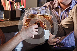 Happy friends drinking beer at counter in pub