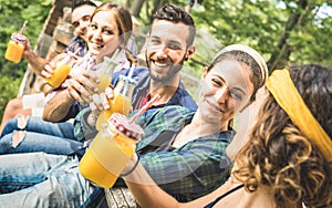 Happy friends drinking healthy orange fruit juice at countryside picnic - Young people millennials having fun together outdoors photo