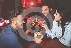 Happy friends drinking and toasting cocktails in a jazz bar - Young people cheering and laughing together in a club at night