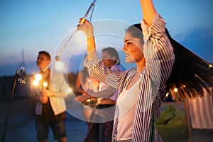 Happy friends with drinks toasting at rooftop party at night