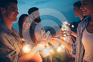 Happy friends with drinks toasting at rooftop party at night