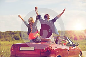 Happy friends driving in cabriolet car at country