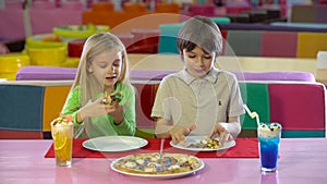 Happy friends eating chocolate pizza at children`s entertainment center.