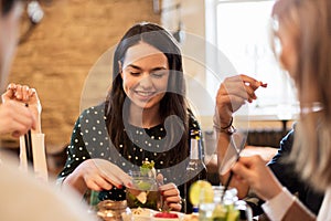 Happy friends eating and drinking at bar or cafe