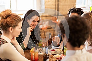 Happy friends eating and drinking at bar or cafe