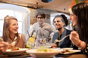 Happy friends eating and drinking at restaurant