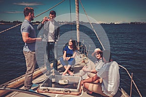 Happy friends eating fruits and drinking on a yacht