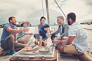 Happy friends eating fruits and drinking on a yacht