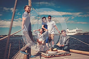 Happy friends eating fruits and drinking on a yacht