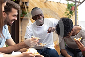 Happy friends eating pizza together, laughing at funny joke
