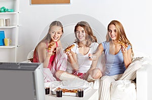 Happy friends eating pizza and watching tv at home