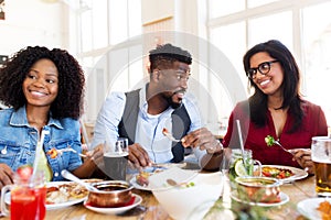 Happy friends eating and talking at restaurant