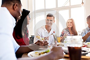 Happy friends eating and talking at restaurant