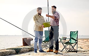 Happy friends with fish and fishing rods on pier