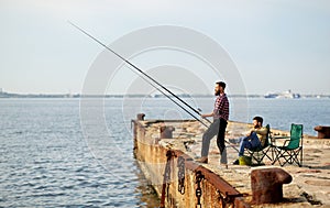 Happy friends with fishing rods on pier