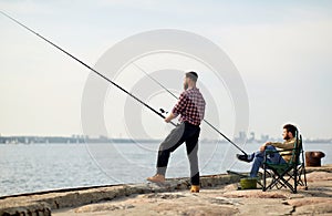 Happy friends with fishing rods on pier